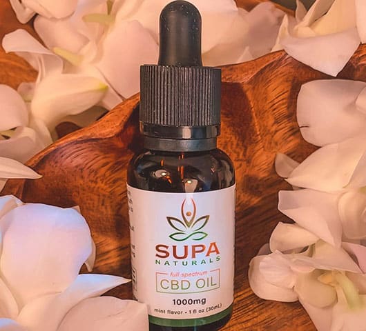 supa naturals cbd oil with flowers on the background
