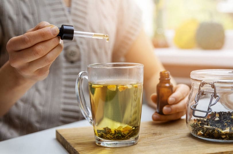 woman putting cbd oil in her tea