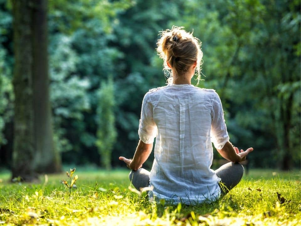 woman meditating in the woods