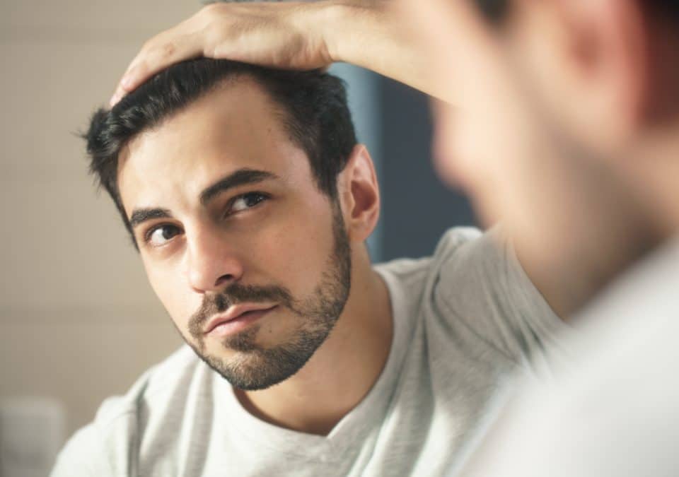 man checking for hair loss at the mirror