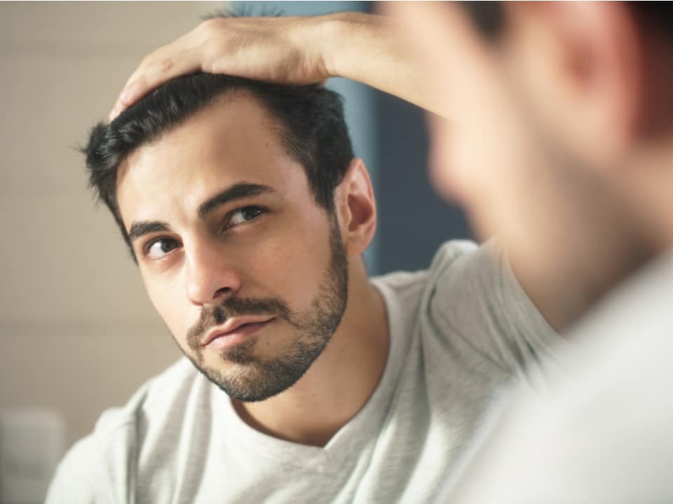 man checking for hair loss at the mirror