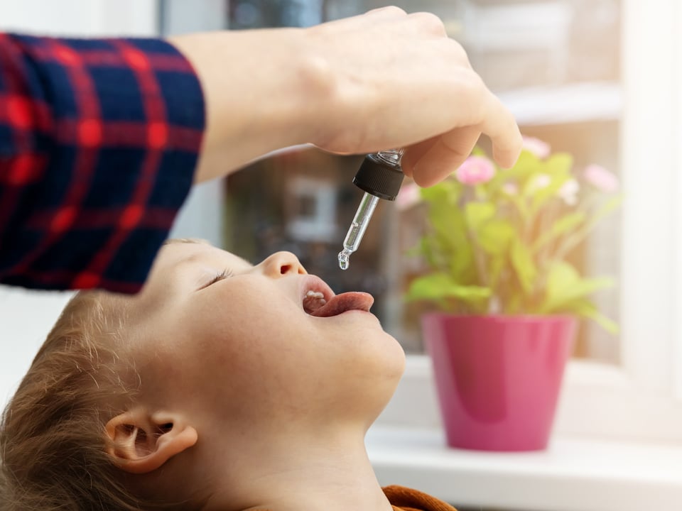 mother giving cbd drops to her kid