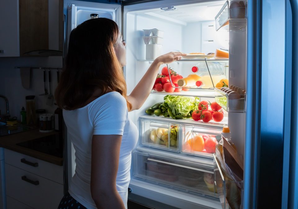 woman checking food items on the refrigerator