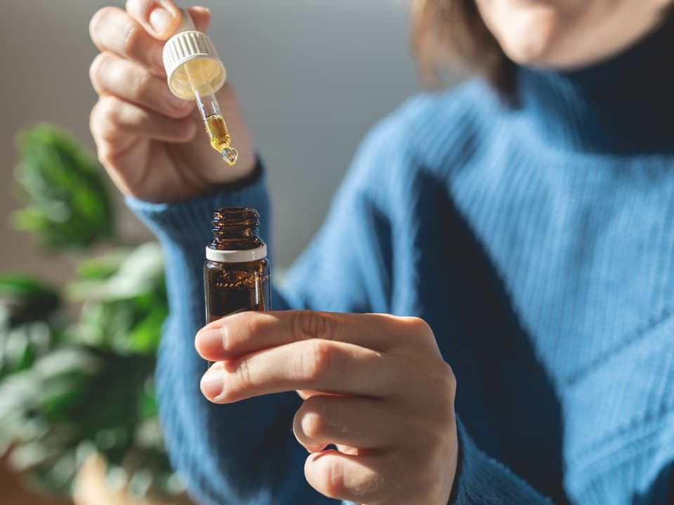 woman extracting a refrigerated cbd oil using a dropper