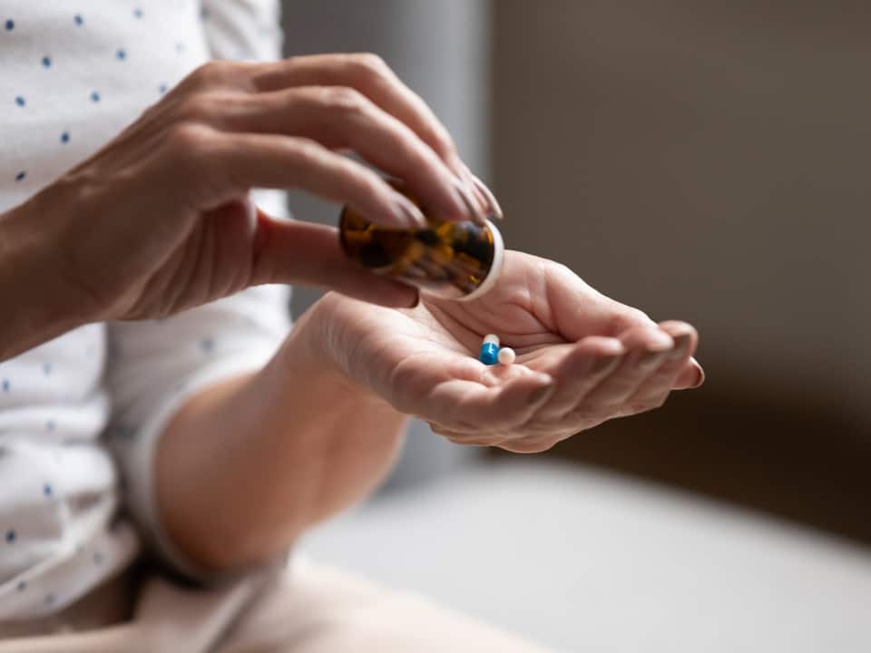 hand pouring out pills from a bottle
