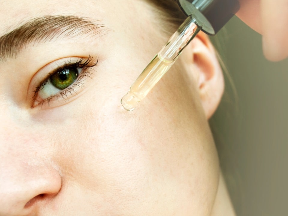 woman applying cbd oil to her face