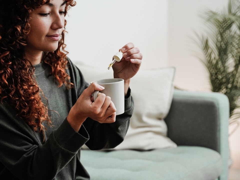 woman dropping a cbd oil in her tea