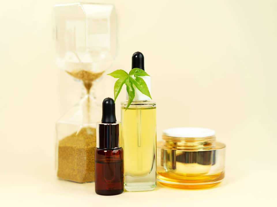 glass bottle with cbd oil tincture cream and hourglass