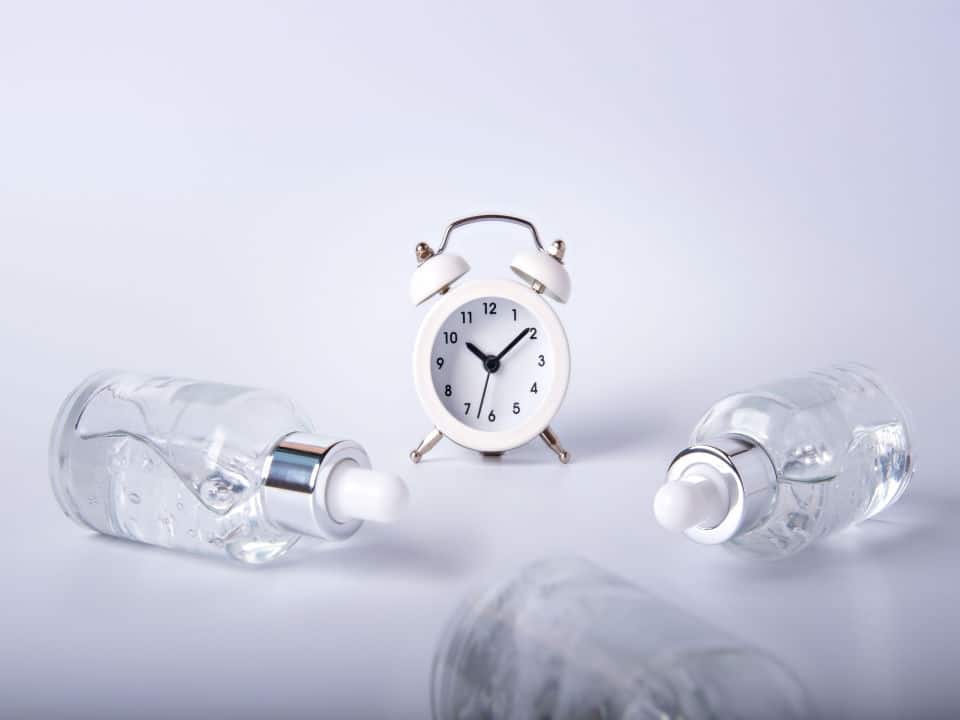 three bottles of cbd oil and a clock in white background