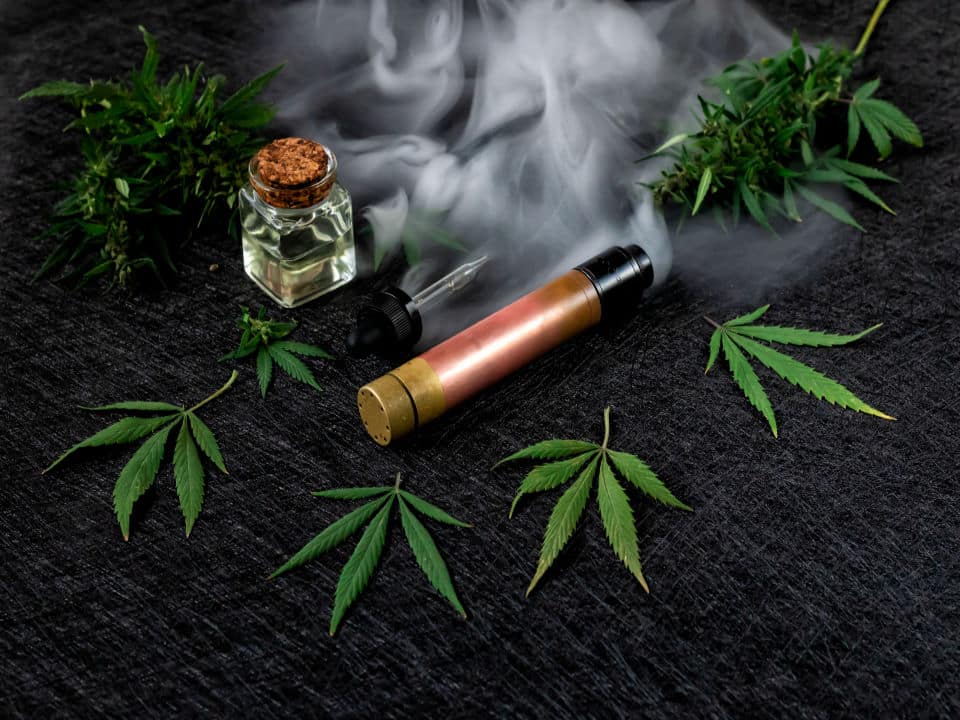 vape kit and cbd oil in dark background with thick steam