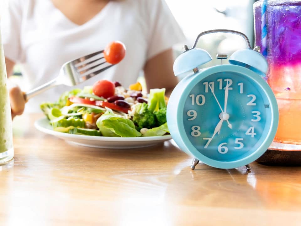 blue clock and a woman make a intermittent fasting with a healthy food