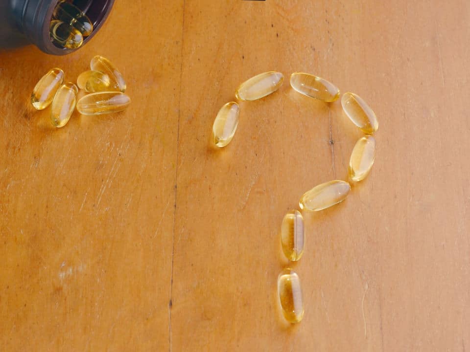 cbd capsule form a question mark on wooden table