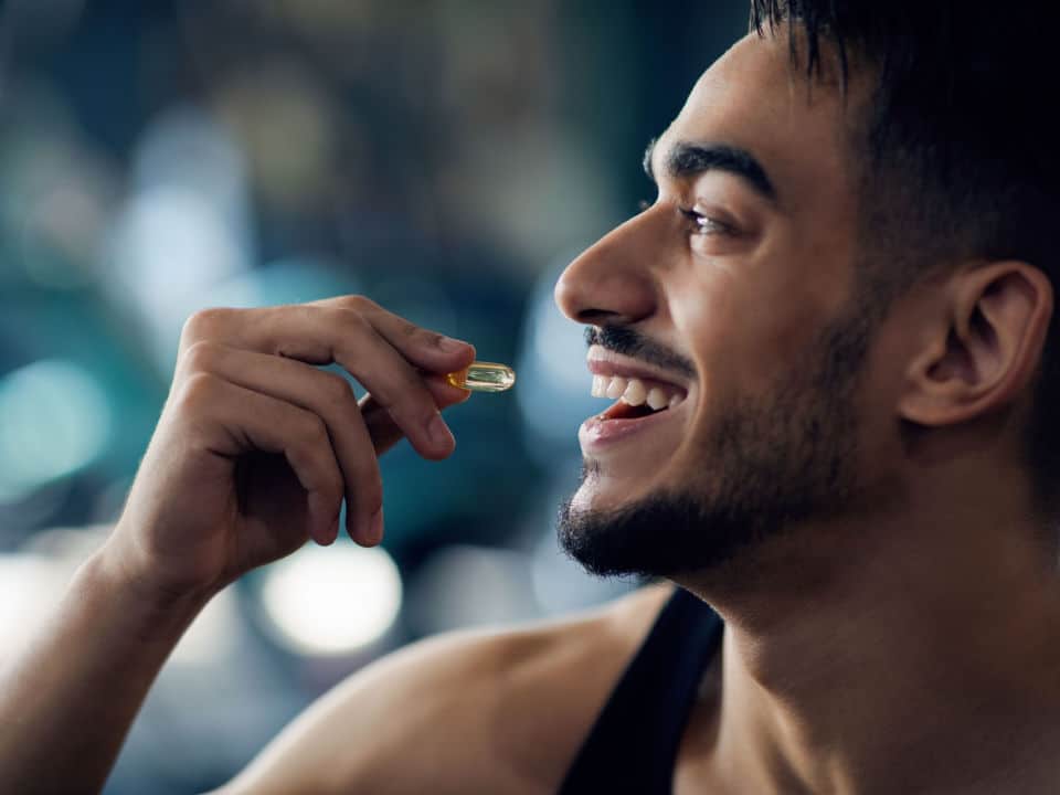 man taking cbd capsule before starting his workout on gym