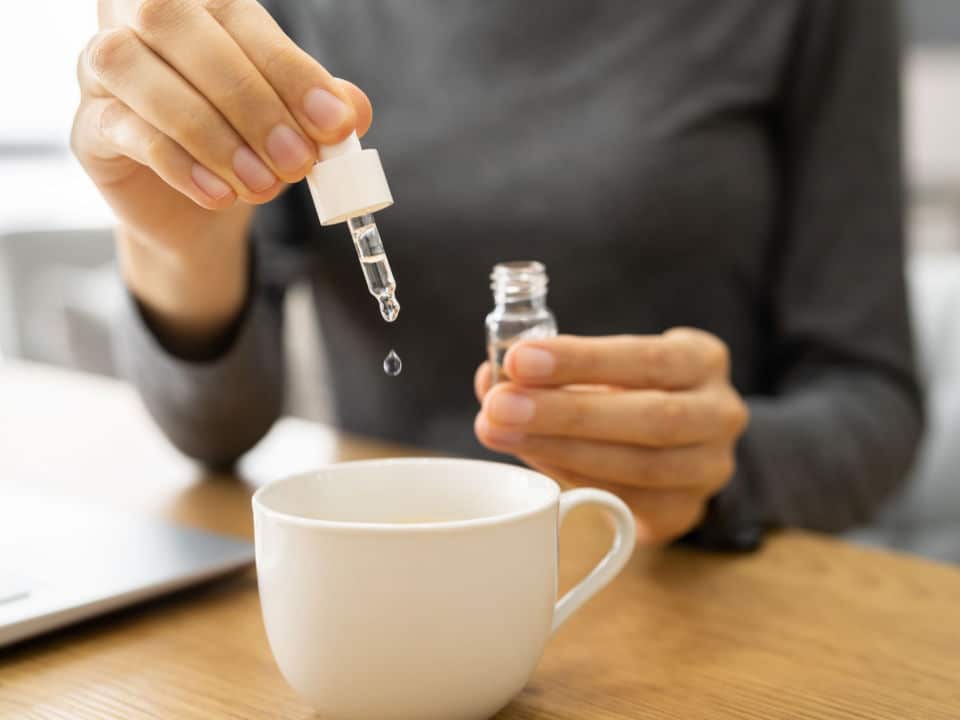 woman putting water soluble cbd oil in her tea