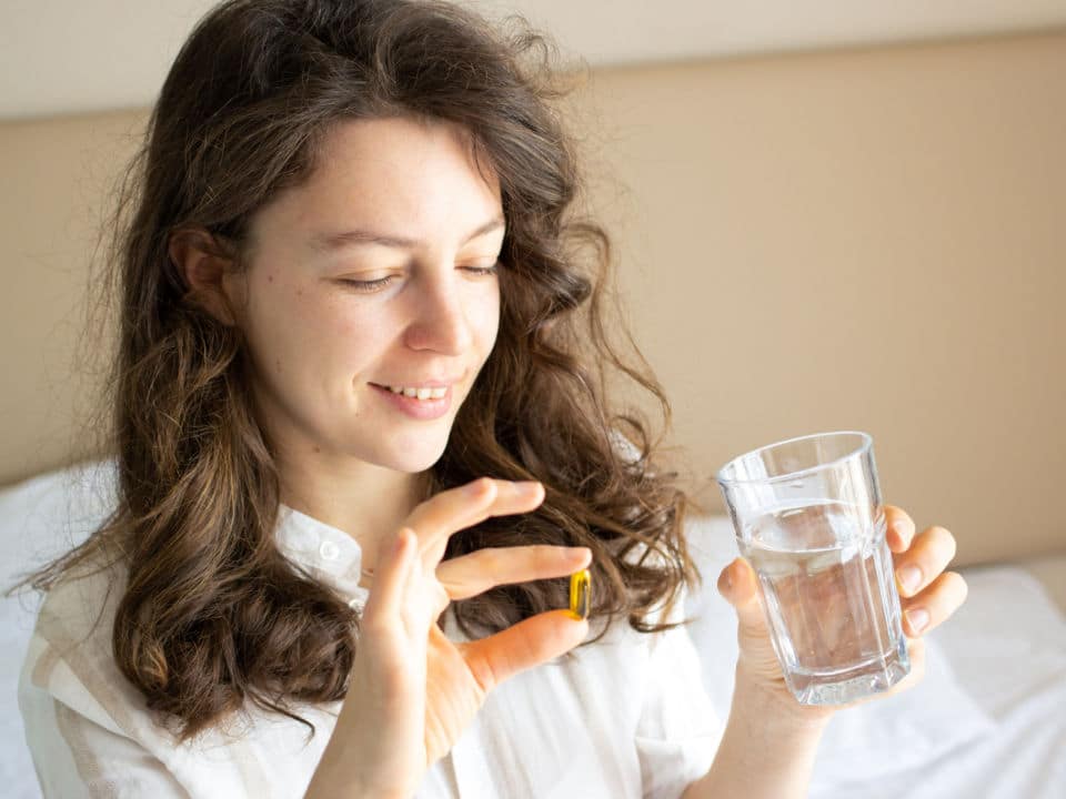 woman taking cbd capsule in bed after sleep
