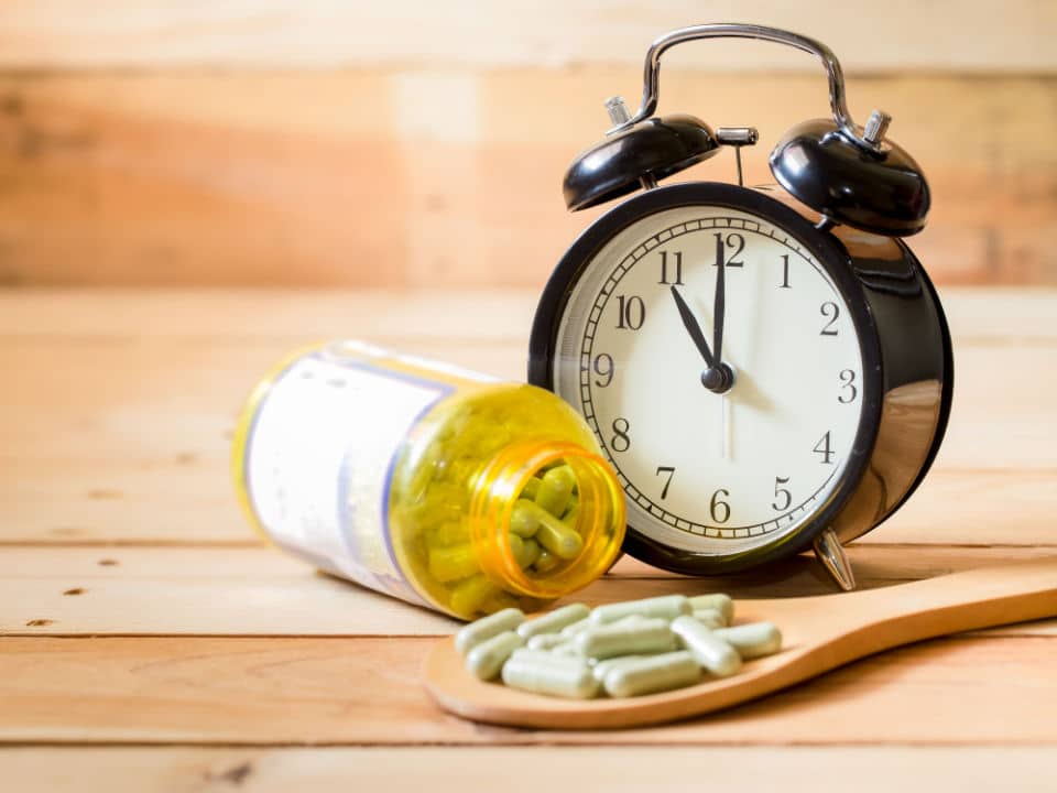 cbd capsule with clock on wooden table