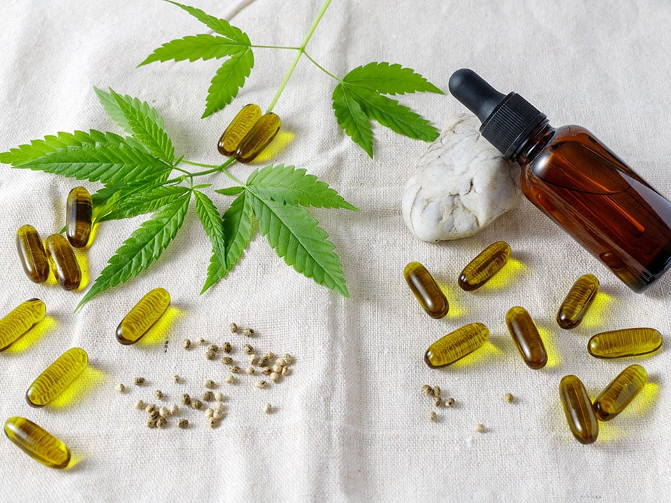 cbd oil capsules and leaves on fabric background