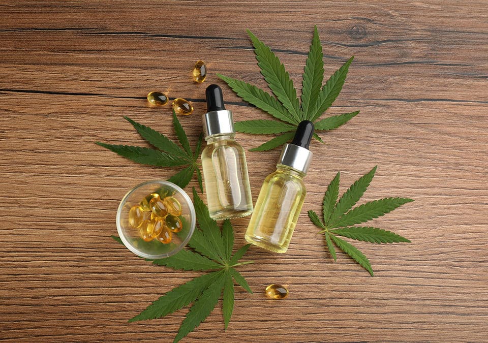 cbd oil thc tincture capsules and hemp leaves on wooden table