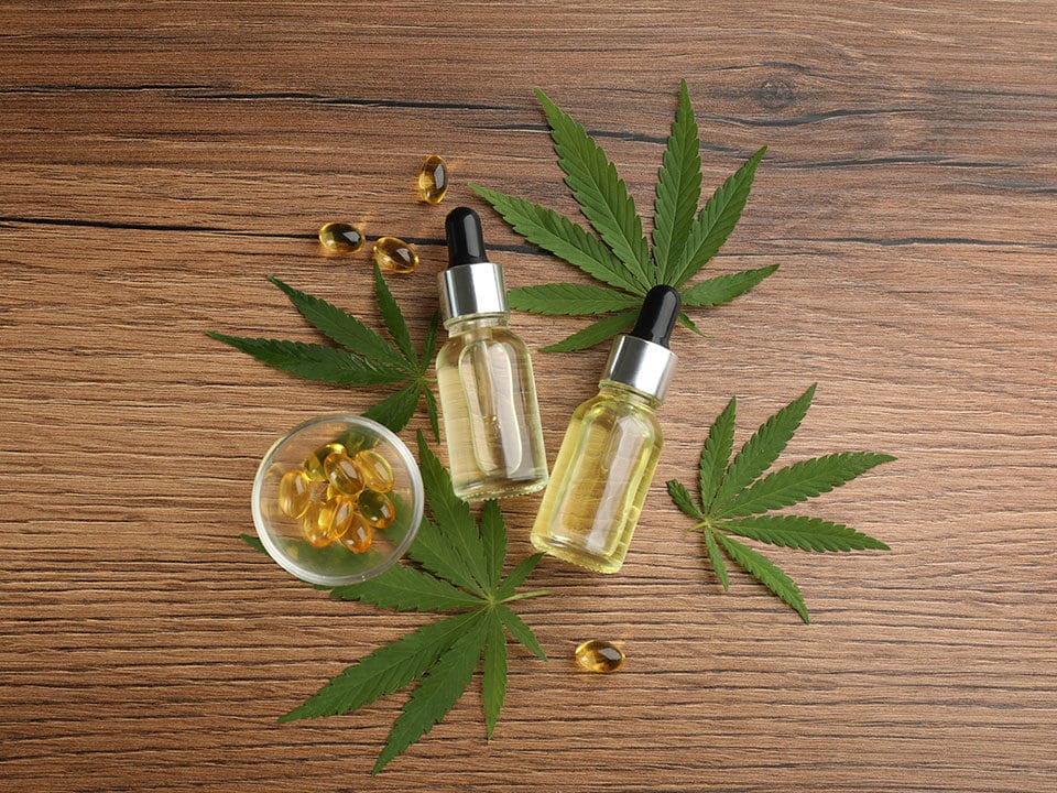 cbd oil thc tincture capsules and hemp leaves on wooden table