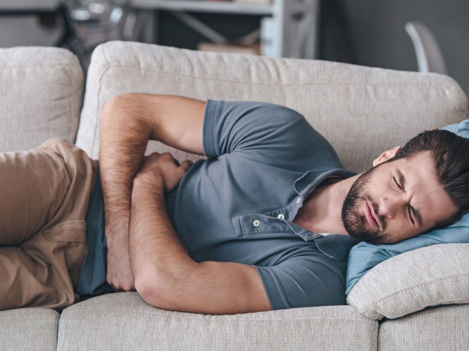 man hugging his belly having stomach ache